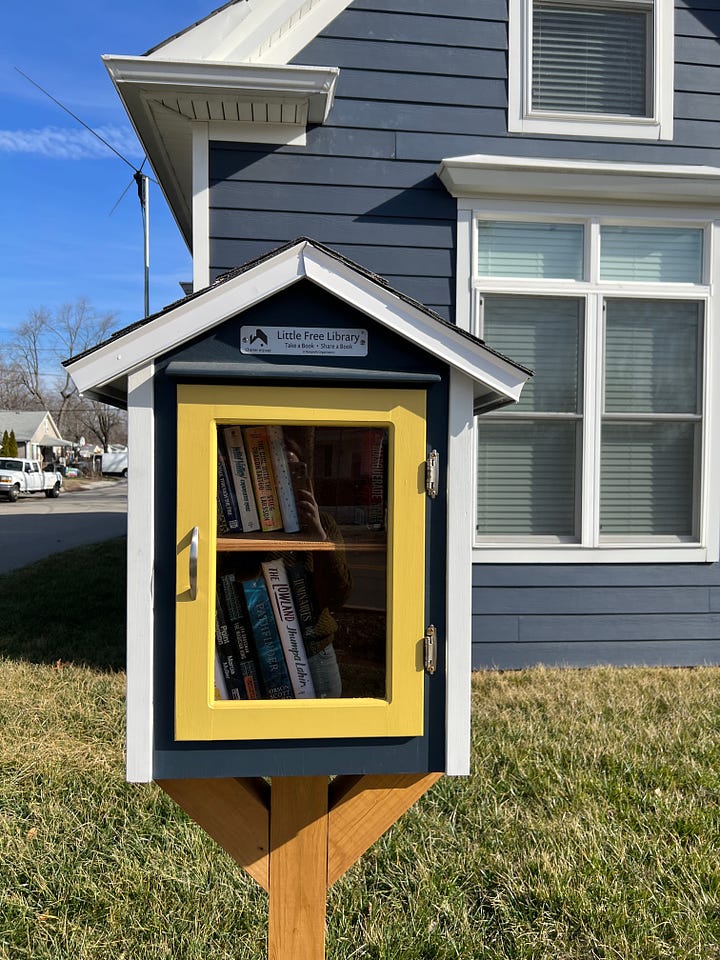 Four images of different Little Free Libraries. The top left image shows a hand holding up a copy of Our Missing Hearts by Celeste Ng in front of one of the libraries. 