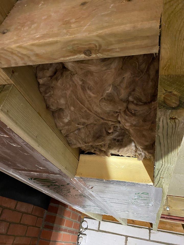 garage ceiling with sheets of insulation being applied into the gaps