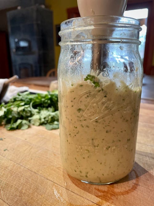 On the left a jar with mixed lemon pith and a stick blender in the jar. On the left a cracker with the finished fermented lemon pith dip.