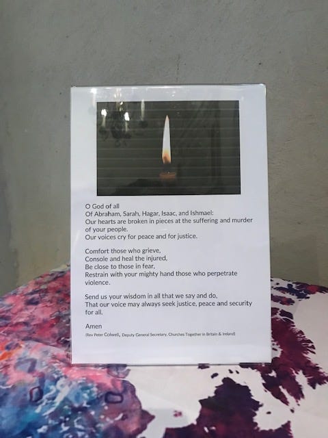 text of a prayer for those suffering in the Israeli-Palestine conflict today and also for us; second image includes the background of the stained glass window above the table with a tablecloth showing a map of the world in pink and white and a map of the Gaza strip and surrounding area including Jerusalem and Bethlehem