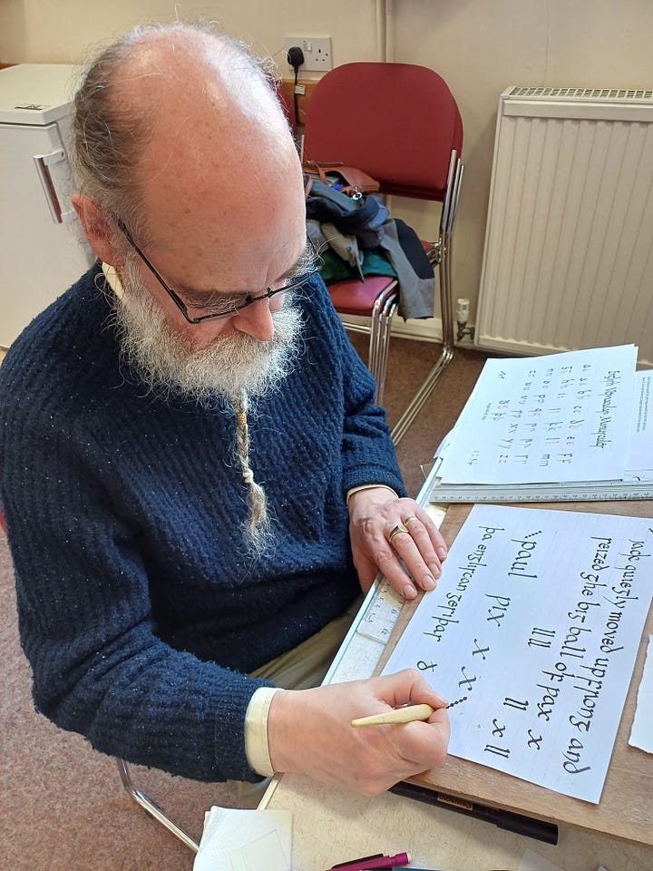  A bearded man wearing glasses is focused on writing on a sheet of paper at a desk; A woman diligently writes on a piece of paper, focused on her task with a pen in hand; A group of individuals gathered at tables, engaged in discussion with papers and coffee cups in front of them; A classroom scene featuring individuals seated at tables, engaged with papers and pencils for learning activities.