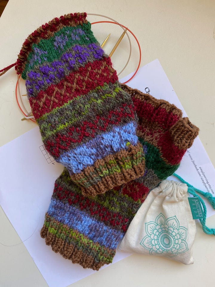 Four partially finished knitting projects. A multicolored pair of Fair Isle mitts, a gray and white sace beret, a bright yellow and gold basket weave lace scarf, and soft teal scarf.