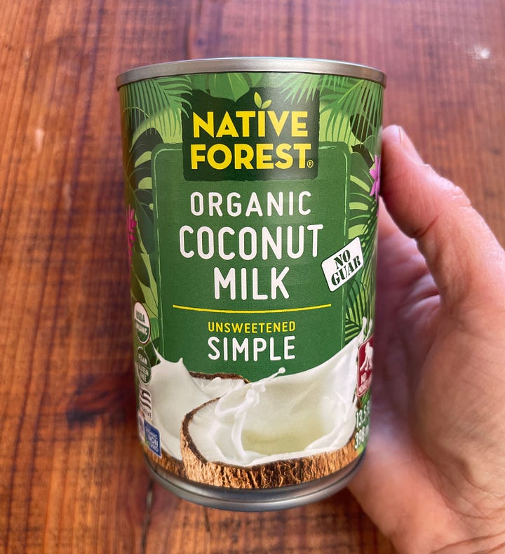 A hand holding a can of organic coconut milk; a glass jar of homemade coconut milk