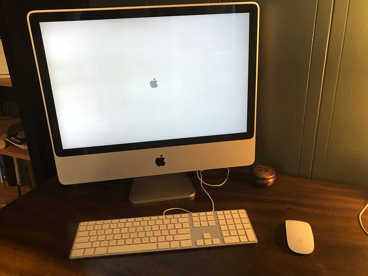 Two photos.  The first is a 21 inch 2007 iMac on a wooden desk with a boot screen, a silver and white keyboard and a Magic Mouse.  The second photo is a beige 1997 Apple Power Macintosh G3 Minitower, a 1999 PowerMac G3 blue & white, and a 2006 Mac Pro all sitting on a wooden table.