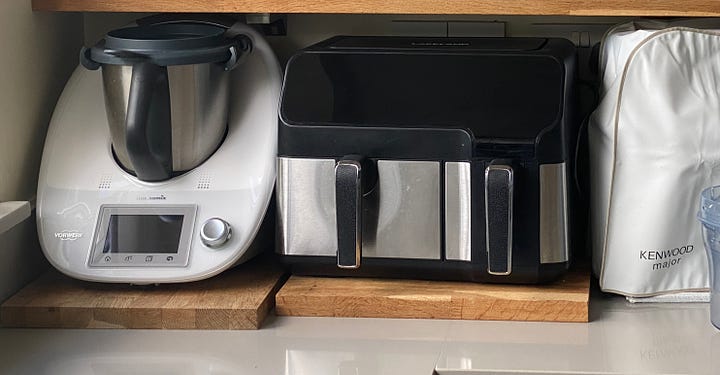 Laptop, airfryer and Thermomix on a counter top.