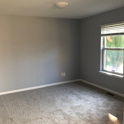 Images show an empty room with grey walls, beige carpet and one window 