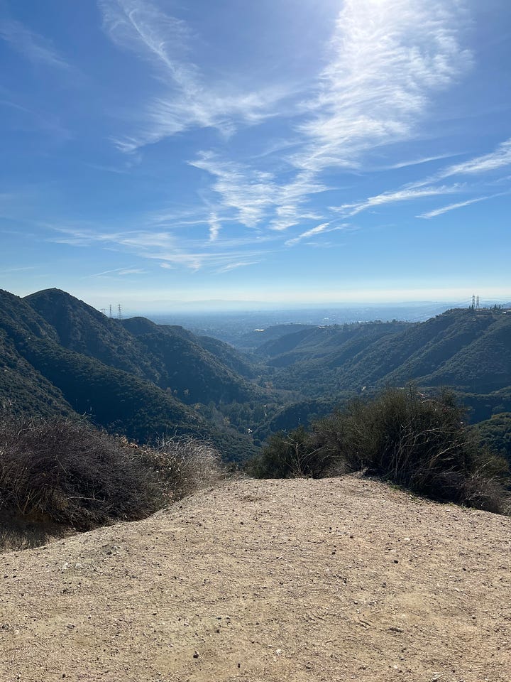 On the right, is a photo of a large green mountain featuring light brown gravel and a clear blue sky. On the right is a view of the Los Angeles skyline featuring a light brown gravel, a clear blue sky but a thick layer of smog in the distance. 