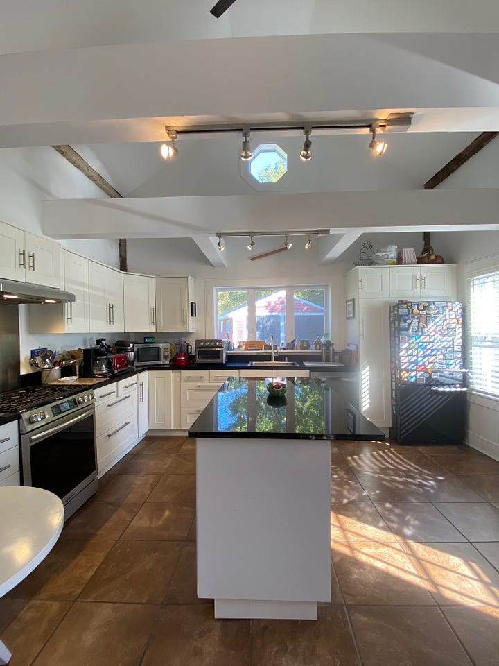 Kitchen with white cupboard doors and walls, and black counter tops.