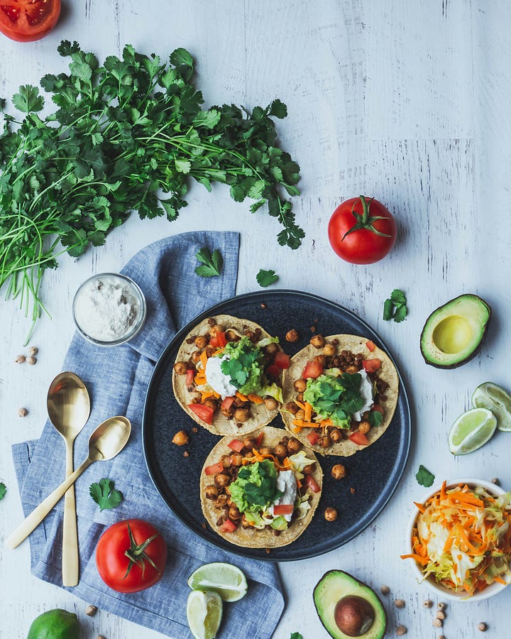 Taco spread with lots of salsas and toppings. Vegan chickpea and lentil tacos with cilantro, avocados, tomatoes, and limes. Photos by ALLAN LAINEZ and Shannon Nickerson, Unsplash