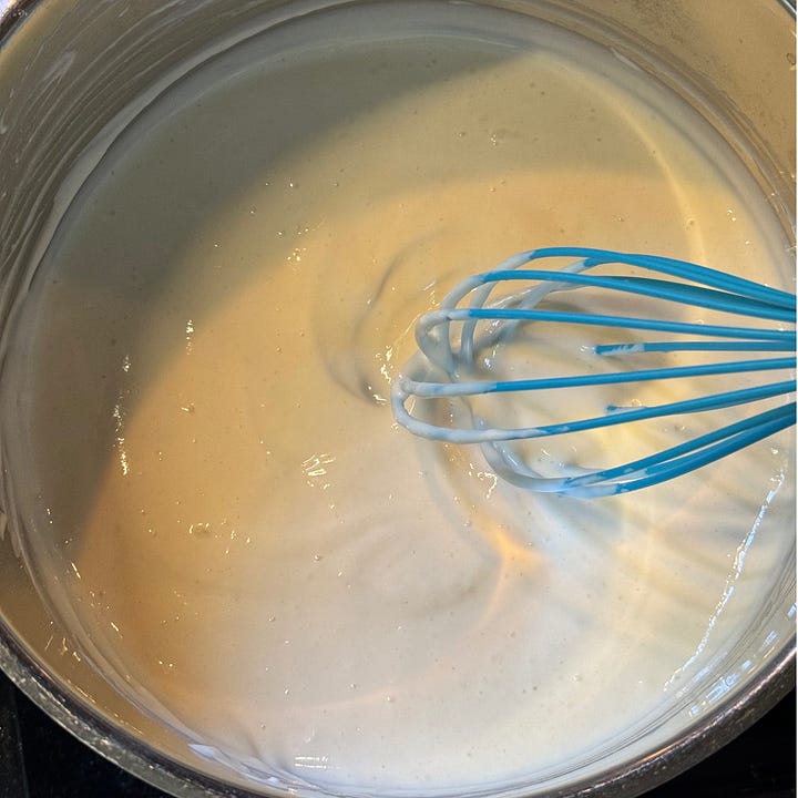 whisking tangzhong, a roux with milk and flour, with a whisk in a silver pot