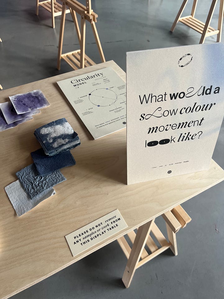 1-2. Exhibition table for 'blues' from Slow Painting Studio showing samples of blue paints on paper derived from kitchen food waste scraps.