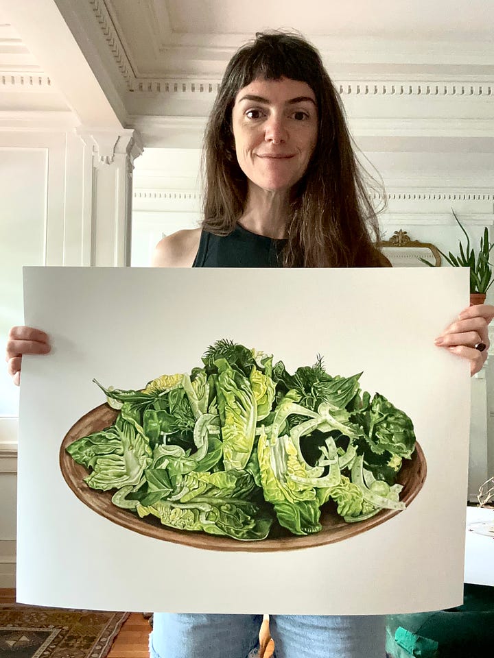 The image to the left shows me holding up a large print of a little gem lettuce salad with fennel and dill. The image on the right shows me holding a large print of a breakfast spread- tea, focaccia, cucumer, tomatoes, cheese, butter, apricot jam, all spread on plates ontop of a blue tablecloth 
