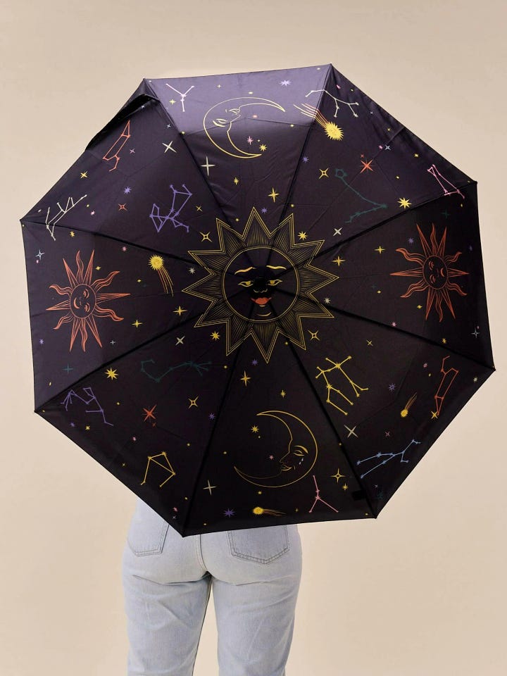 Black umbrella with Halloween zodiac symbols in white, featuring Original Duckhead’s signature duck-head handle. Made from recycled materials, perfect for eco-conscious, spooky-season style