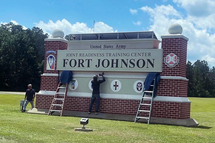 Black army set in uniform, brick sign at Fort Johnson