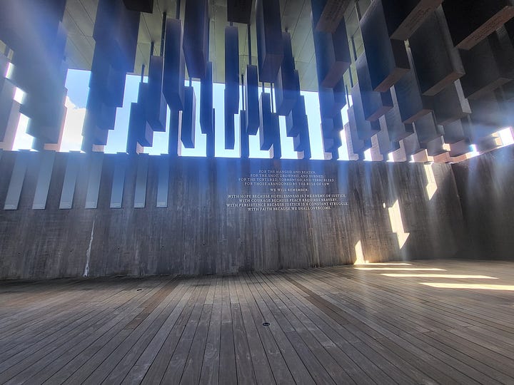 Bronze of Rosa Parks, historic marker by MLK's Dexter Avenue Baptist Church, names of justice nonprofits etched into a black wall, tomb-like structures listing those killed by lynching, shown laying like a coffin and hanging above