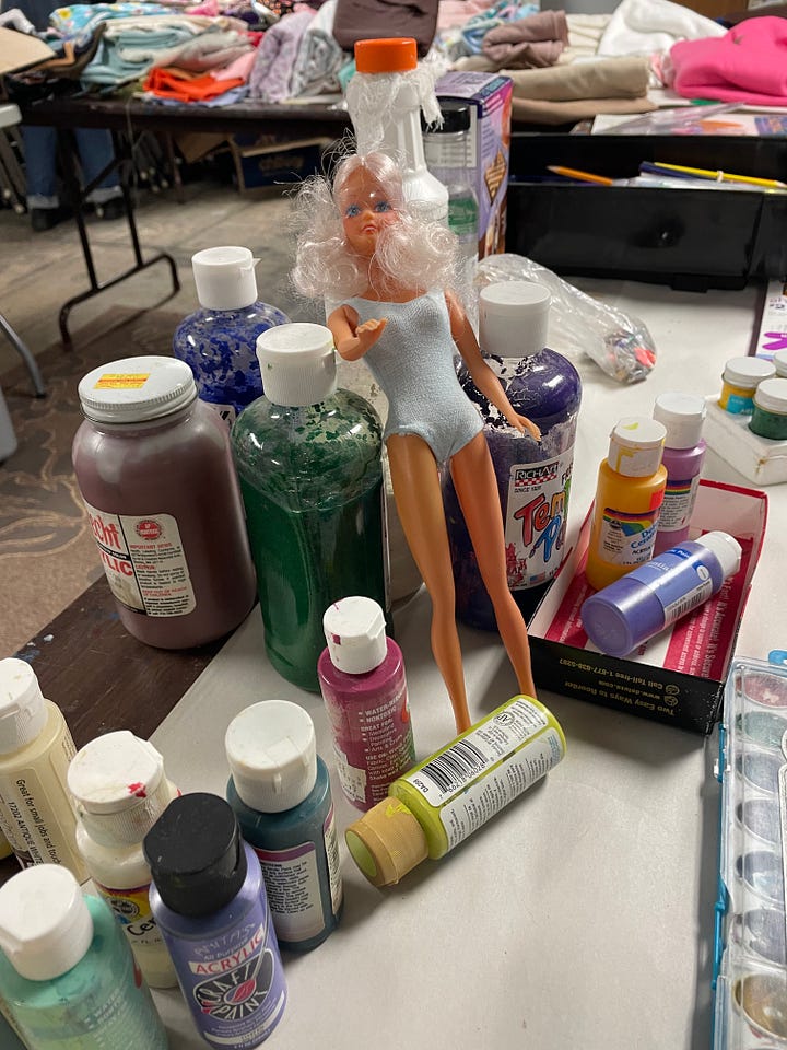 Swap tubs in a retail store, empty tables arranged in a basement, the same tables beginning to fill with materials, and a wide range of donated supplies on those tables from paint to frames.