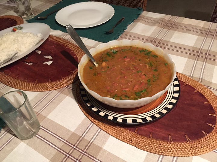 Image 1: white bowl filled with rajma dal on a brown wood placemat; Image 2: Punna, an Indian woman in her 70s, stands in front of a 4-burner stove with 2 silver pots and a sauté pan cooking rajma dal and rice.