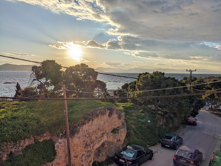 Pictures of the sun setting over the ocean with land in the background