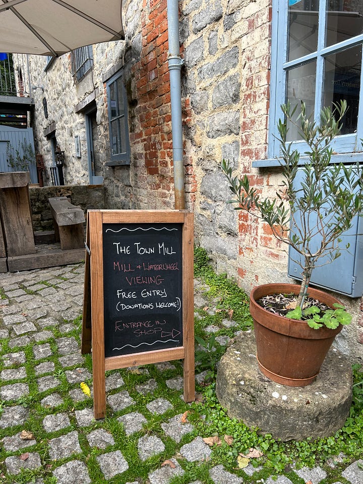 The 4 story building, Town Mill and the second photo is an A-Board inviting people in. Next to the A-Board is a small shrub in a plant pot. Images: Roland's Travels