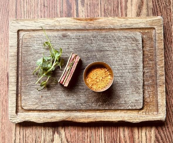 Two images of indigenous food cooked by celebrity chef Shane Chartrand, set out on wooden boards. 