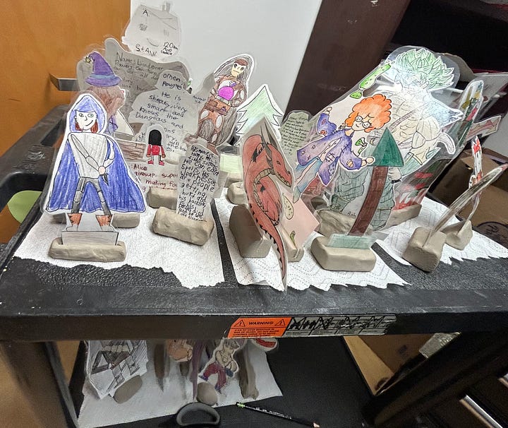 Images of characters drawn by students, cut out of paper, laminated and mounted in air dry clay so they stand up. 