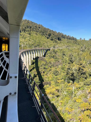 A set of 4 pictures taken from the window of the long-distance train - showing railroad tracks, green bush, and sweeping lake vistas out of a train window