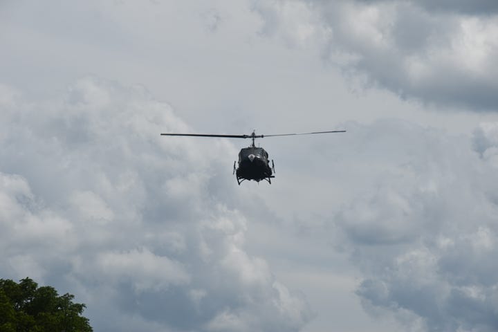 Two photos of Huey helicopters in flight with cloudy skies above.