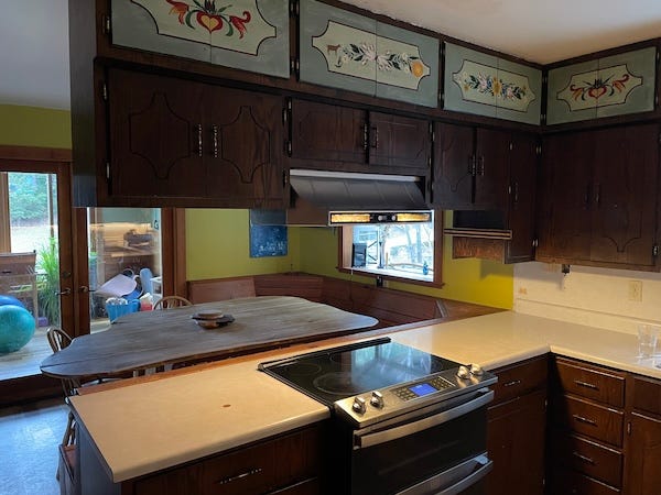 Two photos of before and after a kitchen remodel. Dark cabints on the left and photo on right shows the removed with a new free hanging stove fan.