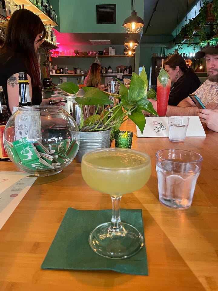 Bialy and dips, piece of lemon olive oil cake, hush puppies, a drink at a tropical-themed bar.