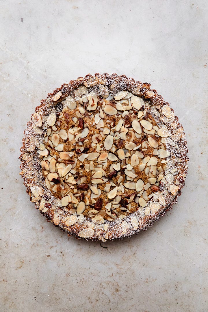 Vegan fresh cherry frangipane tart, including a pastry shell, cherry jam, cherries, almond frangipane and flaked almonds 
