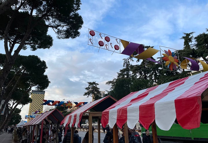 The first image contains traditional Albanian biscuits from Elbasan (bollokume) and "verore" - a summer bracelet given out on the 14th March. The second image contains market stalls and bunting celebrating the day.
