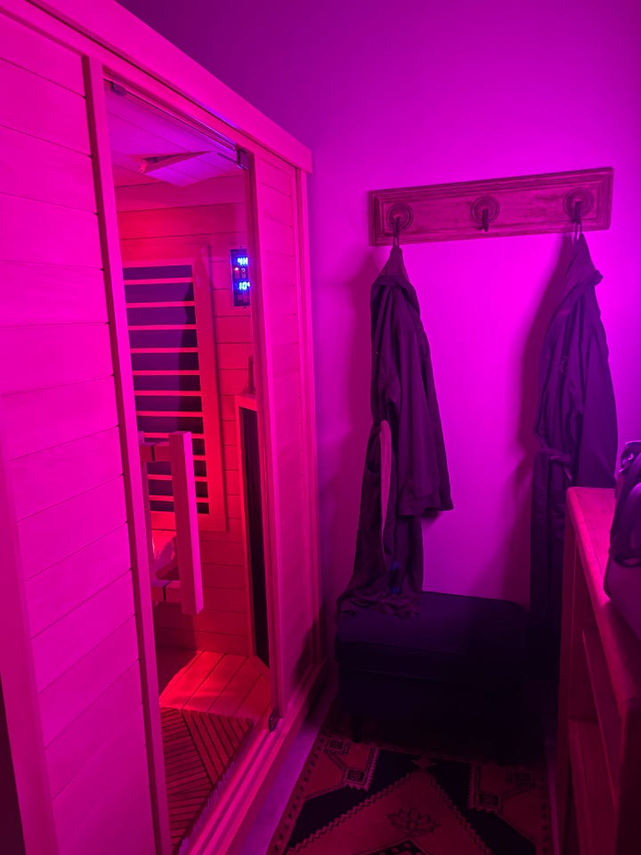 A woman wearing a hat that says "Inner peace MTHRFKRS". A fog-filled morning.  An infrared sauna lit with pink light.