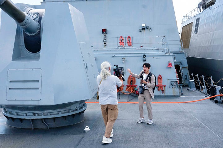 In-port naval open house images including a press conference. One image of the USS Carl Vinson steaming out of Pearl Harbor as a passanger jet takes of at HNL.