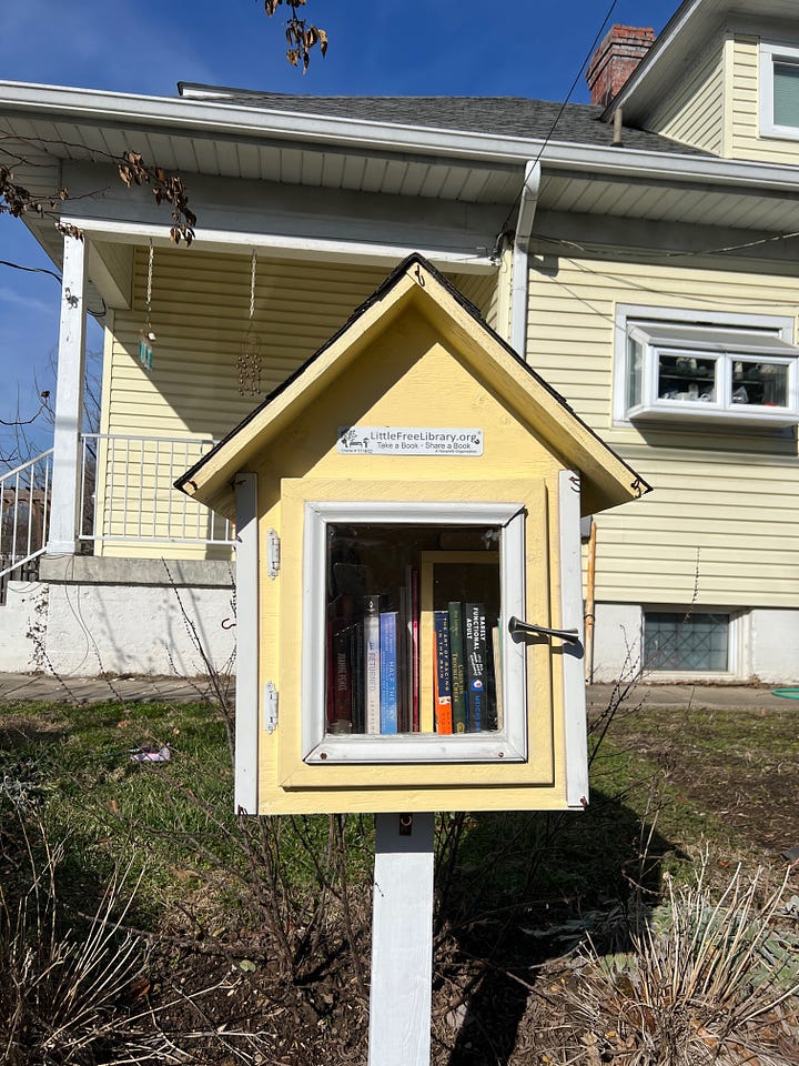Four images of different Little Free Libraries. The top left image shows a hand holding up a copy of Our Missing Hearts by Celeste Ng in front of one of the libraries. 