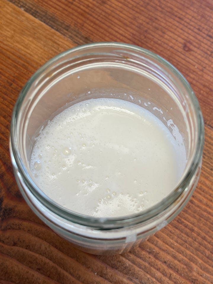 A hand holding a can of organic coconut milk; a glass jar of homemade coconut milk