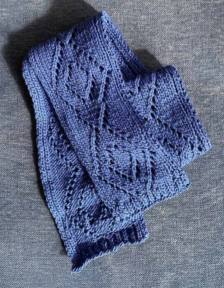 A blue and white snowflake pattern cowl an a narrow blue scarf with a diamond lace pattern