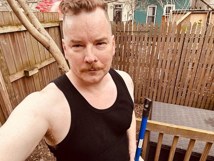Getting sweaty in the backyard in a black tank top and a metal rake.