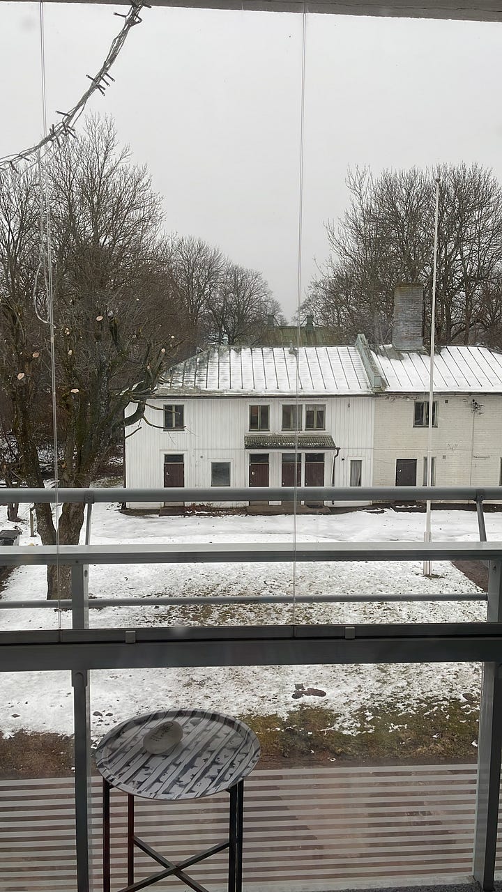 An old, white house with bare trees around, covered in snow. The same house with slightly green grass and sun shining with no more snow 