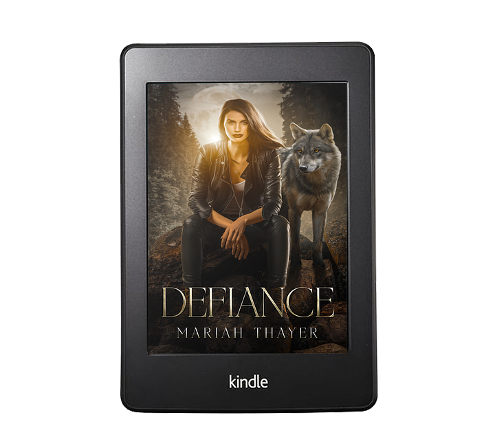 E-readers with the covers of Defiance and Bune by Mariah Thayer on the screen. Defiance features a woman in a leather jacket in the forest with the full moon looming behind her, a wolf at her side. Bune features a woman with short hair wearing a jacket, boots, and scarf walking through a foreboding gray, foggy forest scape.