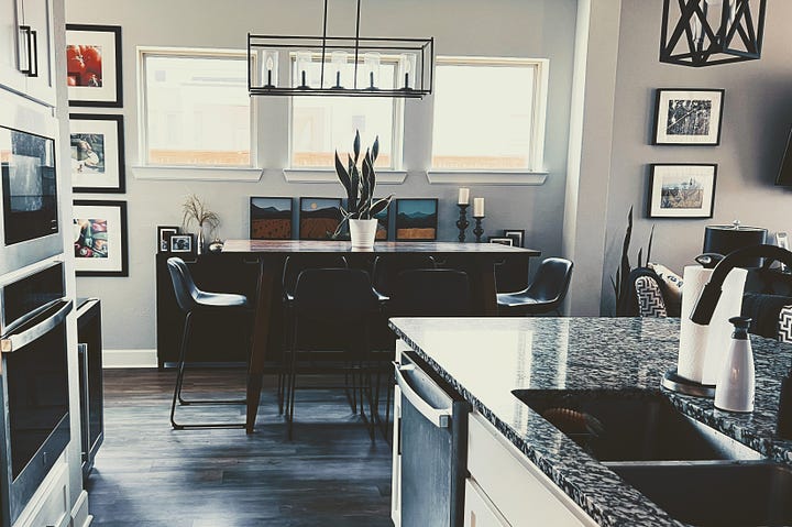 Kitchen with white cupboard doors and marble counter tops.