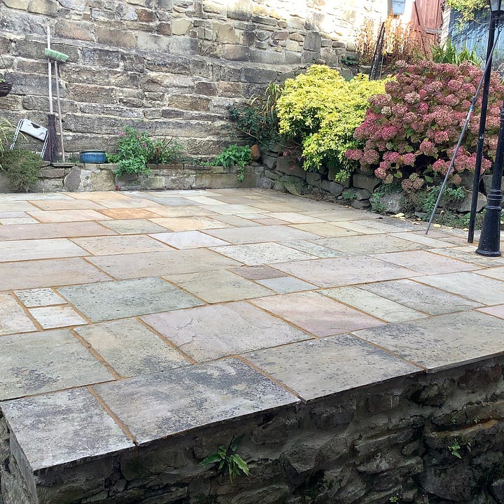 Five pictures of the patio in various stages of repair. First being pressure washed, second, three men is hi-vis clothing are gathered round one flag ‘discussing’ the work needed, third is a pic of lots of lifted flags and a lot of mess, fourth is he revealed steps of York stone and the relaid and regrouted old flags of many colours, the first is a picture of fags that have been regrouted, the grout is ina contrasting colour. 