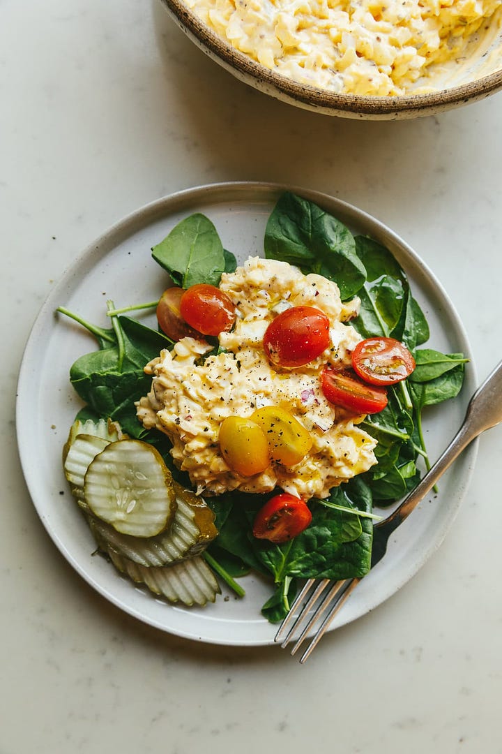 Egg salad ingredients in a mixing bowl and served on a salad.