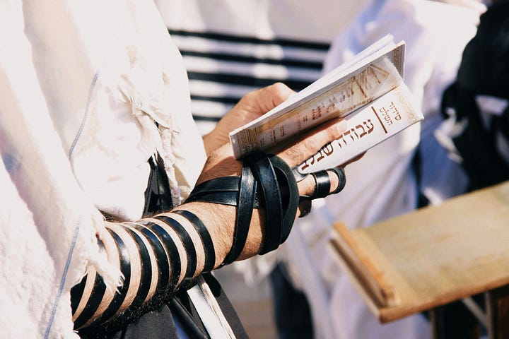Left: tefillin wound on right arm of man holding prayerbook; right: tefillin on a table