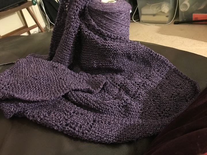 A garter stitch lace shawl and a cone of purple wool
