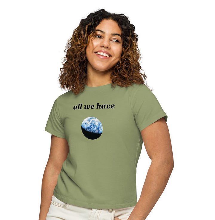 White, grey, and green shirts with black text reading "all we have" in all lowercase with a photo of the Earth in partial eclipse underneath the text. On the back are 6 suggestions including "get to know the plants around you", "reduce, reuse, recycle", and "make trash art".
