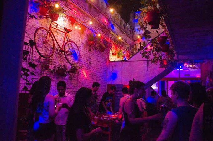 A vintage bike hangs on the walls of the neon -lit patio while two punk tatooed scruffy boys embrace at Feliza Gay & Lesbian Club in Buenos Aires