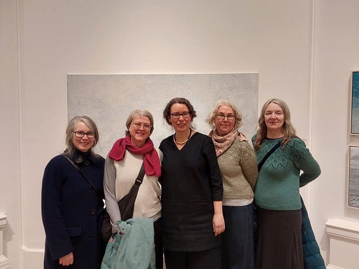 a group of people gathered in an art gallery, all smiling