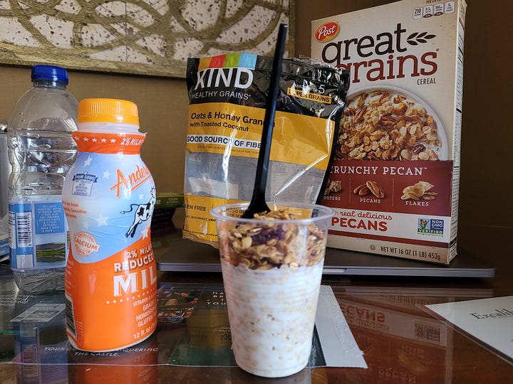 A cheap plastic cup containing granola, milk and a plastic spoon, and a tube of purple lip oil