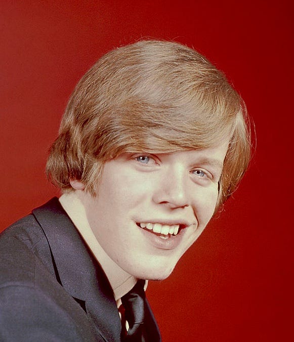 A photo of Peter Noone showing his teeth in the 1960s and a photo of Jeff wearing a hoodie and glasses.