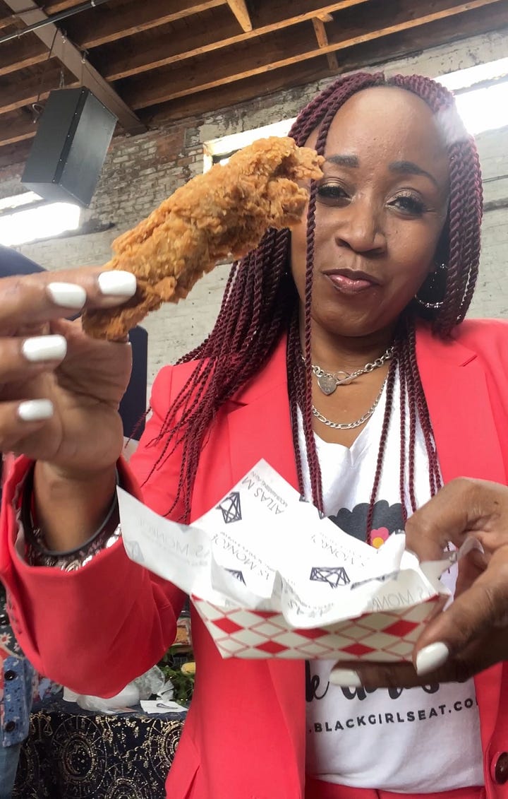A plate of red velvet cupcakes and a woman holding a piece of vegan fried chicken